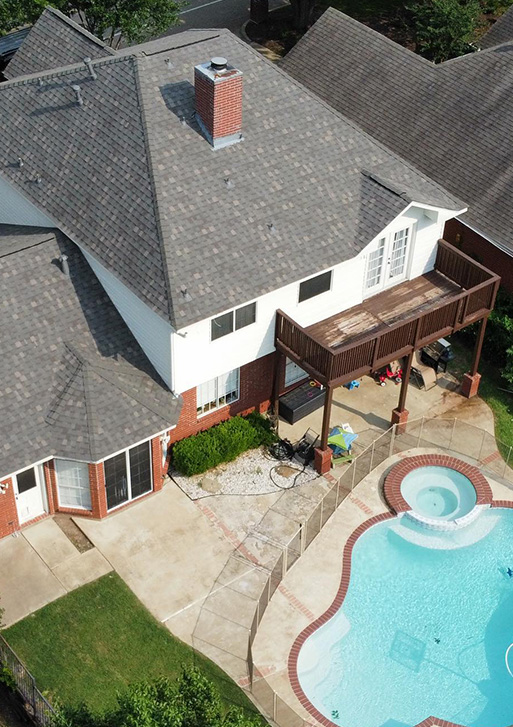 A residential roofing contractor in Dallas offers an aerial view of a house with a swimming pool.